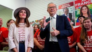 Anthony Albanese and Labor’s candidate for Dickson, Ali France, stand together in a campaign office surrounded by supporters wearing red shirts and campaign posters visible in the background