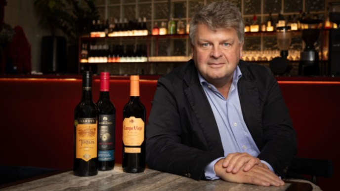 Portrait of Ben Clarke with bottles of wine on a table