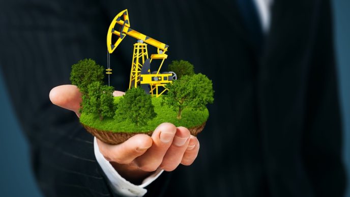 Hand holds oil pump amid greenery