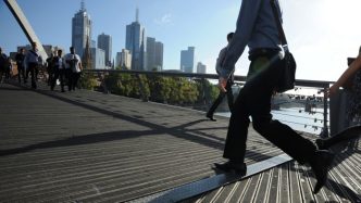 Morning commuters walk across Southgate Bridge in the central business district of Melbourne, Australia