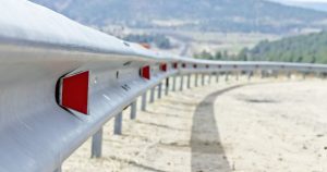 Silver and red rails on the side of a dirt road
