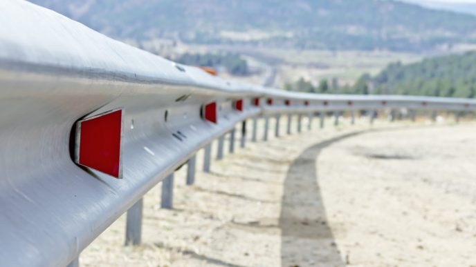 Silver and red rails on the side of a dirt road
