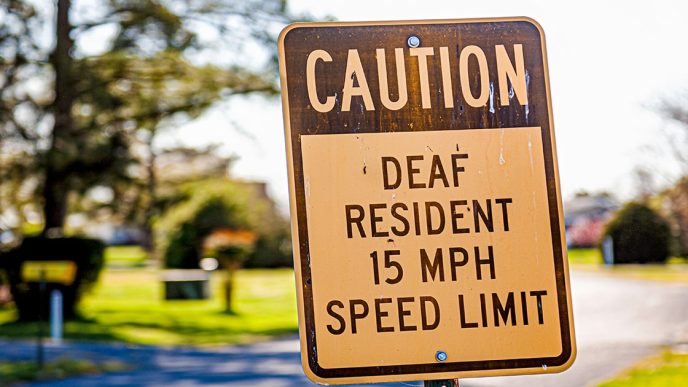Caution deaf resident 15mph speed limit sign in quiet street