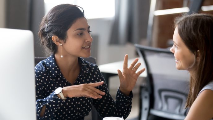 Two women discussing work at a computer desk